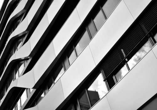 Schwarz/weiss Foto einer modernen und sauberen Fassade, im Fenster spiegeln sich Wolken